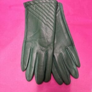 A pair of green leather gloves on a pink background.